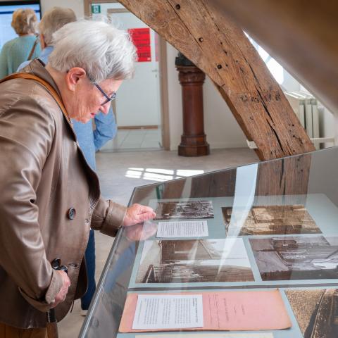 Een bezoeker bekijkt archiefstukken in een vitrine