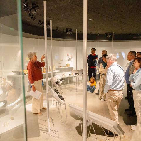 Gids doet uitleg aan een groep geïnteresseerden in het Speelgoedmuseum