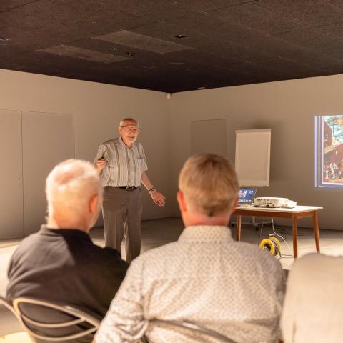 Voorzitter van de dialectvereniging geeft een presentatie met behulp van foto's.