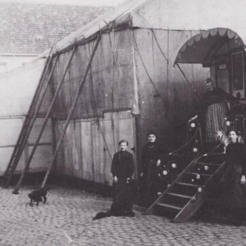 Archieffoto van Circus Ronaldo. Zwartwitfoto waarop verschillende leden van het circus poseren voor een oude tent.